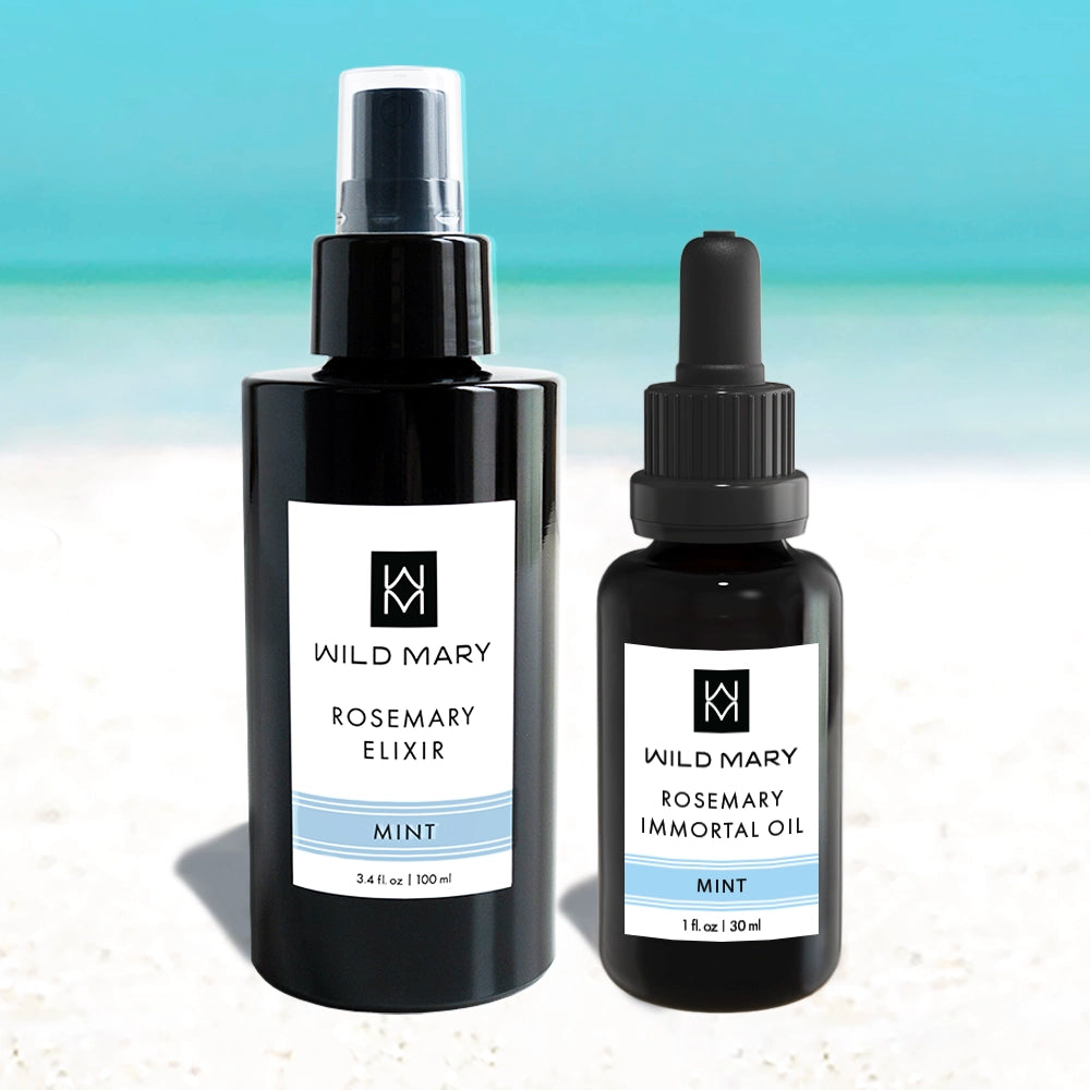 Bottles of Wild Mary Rosemary Mint Elixir and Rosemary Mint Immortal Oil on a light blue and white gradient background.