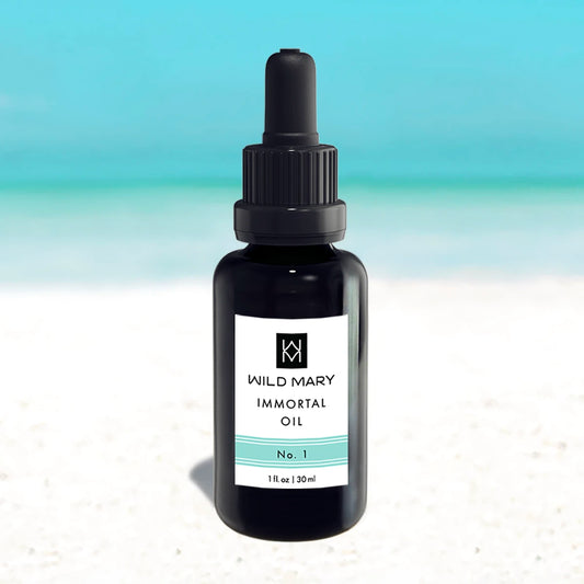 Wild Mary Immortal Oil No. 1 Rosemary Restorative Face Oil in a black glass dropper bottle on Holbox Island beach