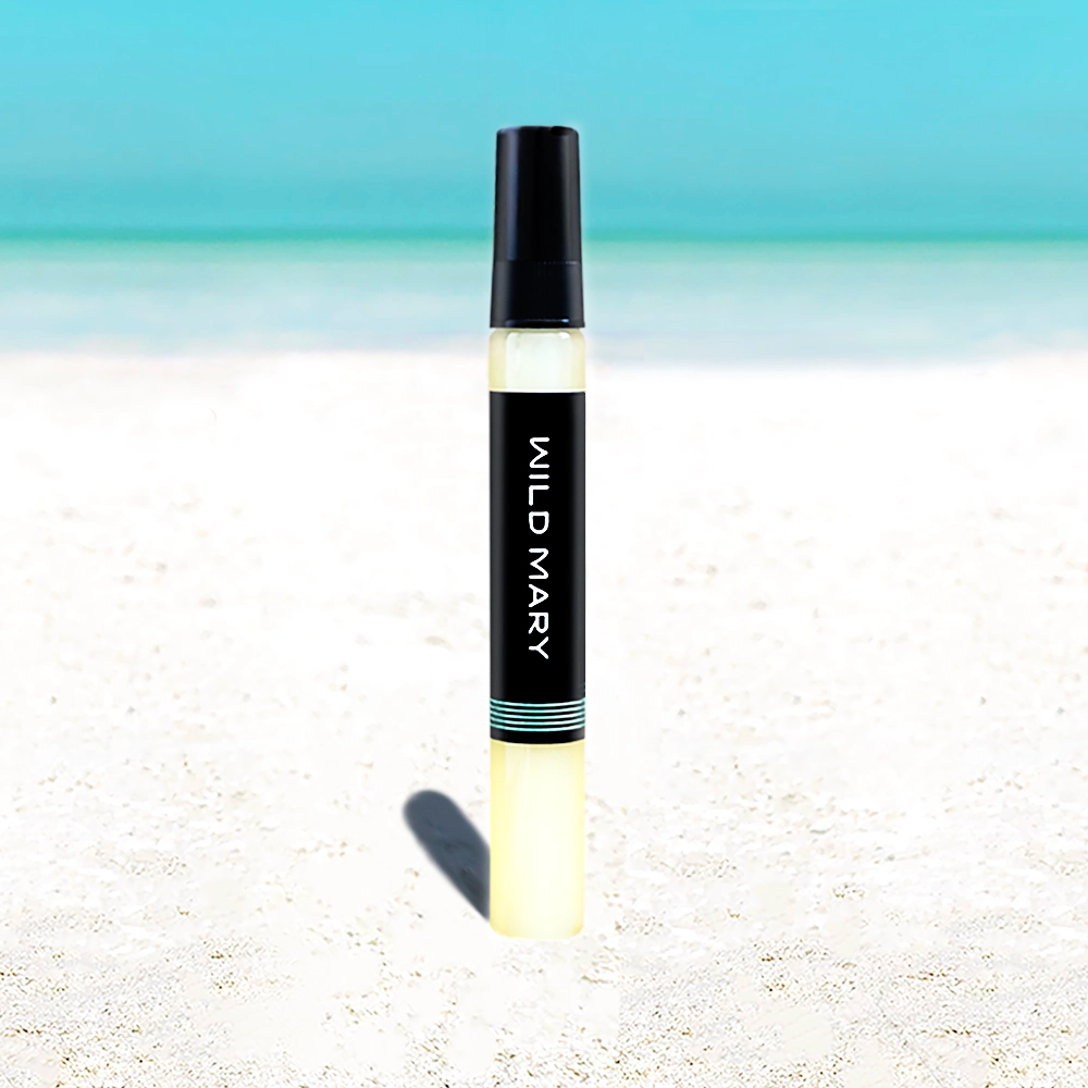 Wild Mary Rosemary Elixir mini — Rosemary variant, travel-size bottle on beach with white sand and blue sky.
