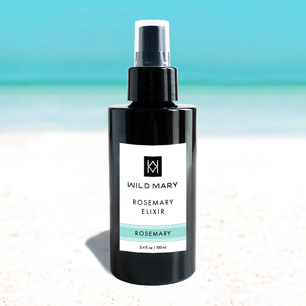 Wild Mary Rosemary Elixir — Rosemary variant, 3.4 oz bottle on a beach background with white sand and light blue sky. 